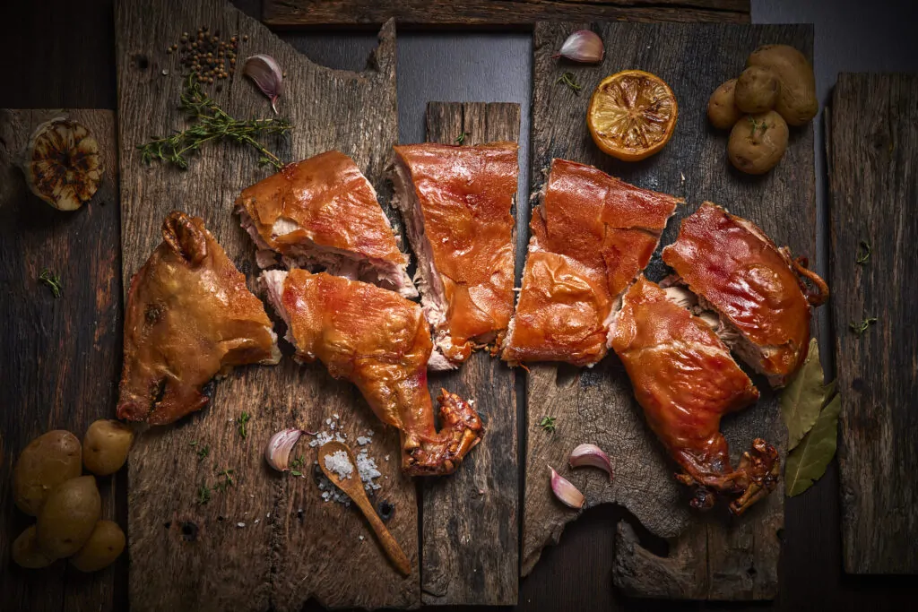 Lechona asada de Safrà, dorada y cortada en porciones sobre tablas de madera